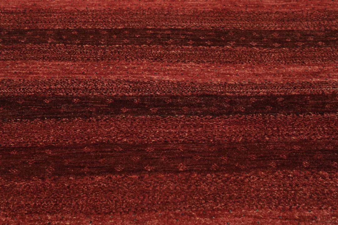 A hand-knotted Loribaft Fine rug from the Middle East in deep red tones.