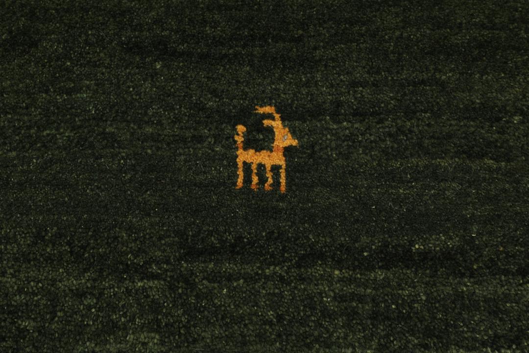 Et håndknyttet Gabbeh-tæppe fra Mellemøsten i en dybgrøn nuance med minimalistiske dyremotiver.