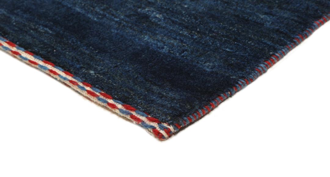 A hand-knotted Loribaft rug from the Middle East in a deep blue colour with small orange accents.