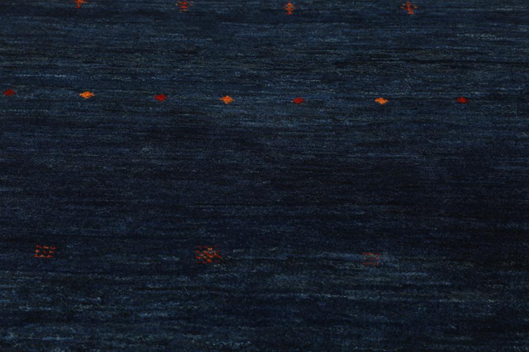 A hand-knotted Loribaft rug from the Middle East in a deep blue colour with small orange accents.