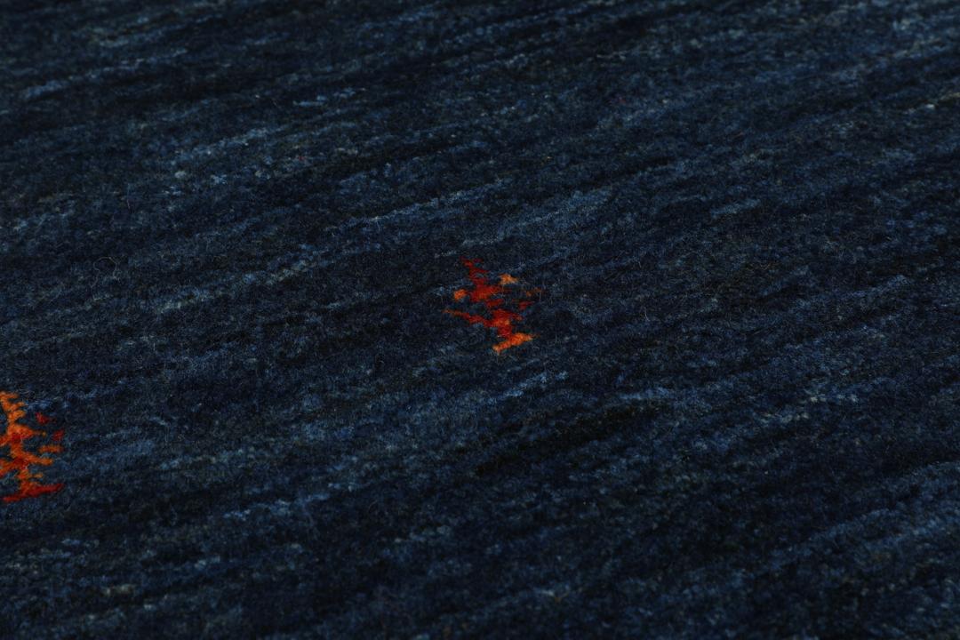 A hand-knotted Loribaft rug from the Middle East in a deep blue colour with small orange accents.