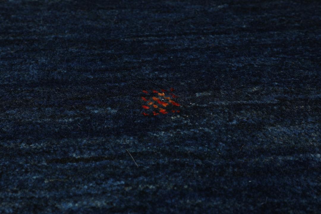 A hand-knotted Loribaft rug from the Middle East in a deep blue colour with small orange accents.