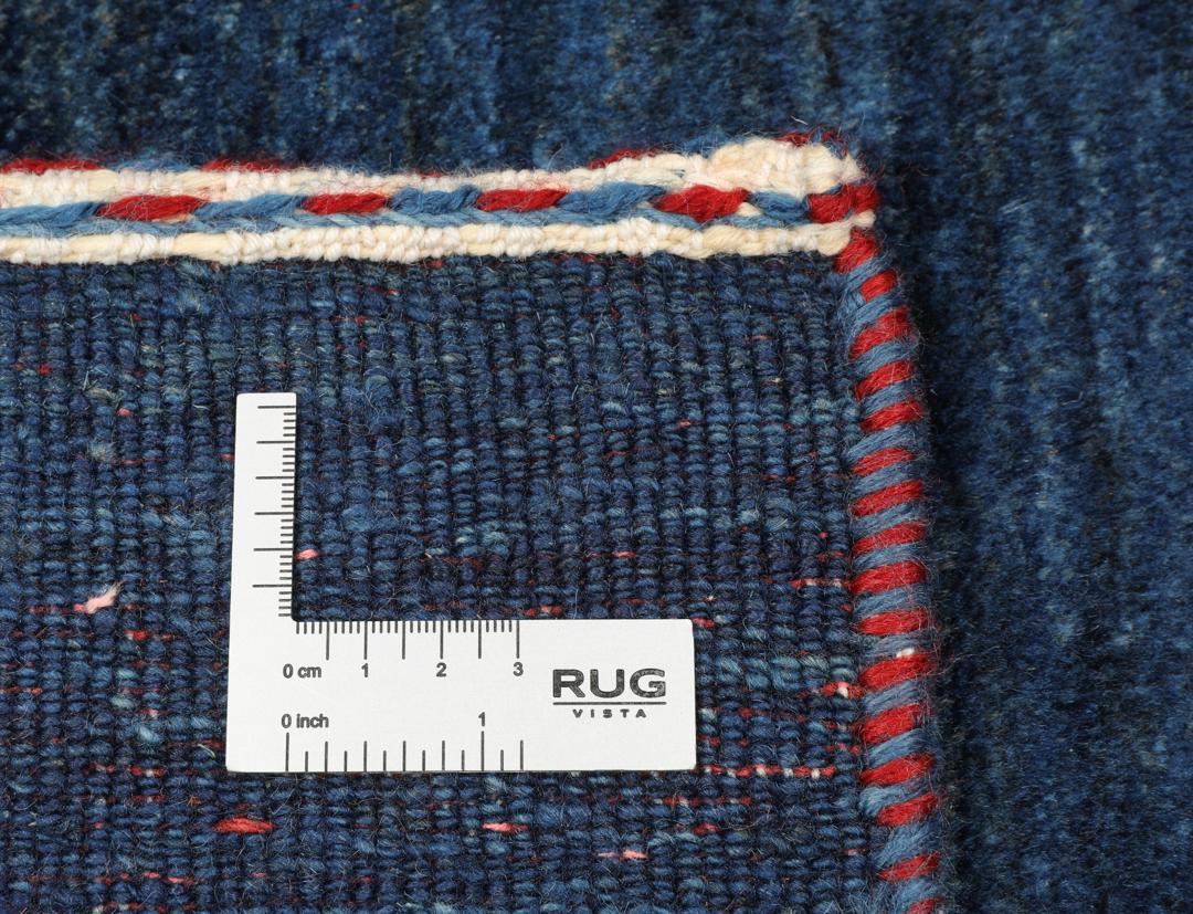 A hand-knotted Loribaft rug from the Middle East in a deep blue colour with small orange accents.