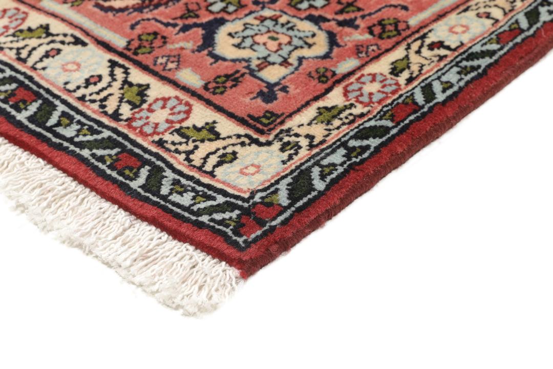 A hand-knotted Senneh rug from the Middle East featuring a dark-red and cream geometric medallion design.