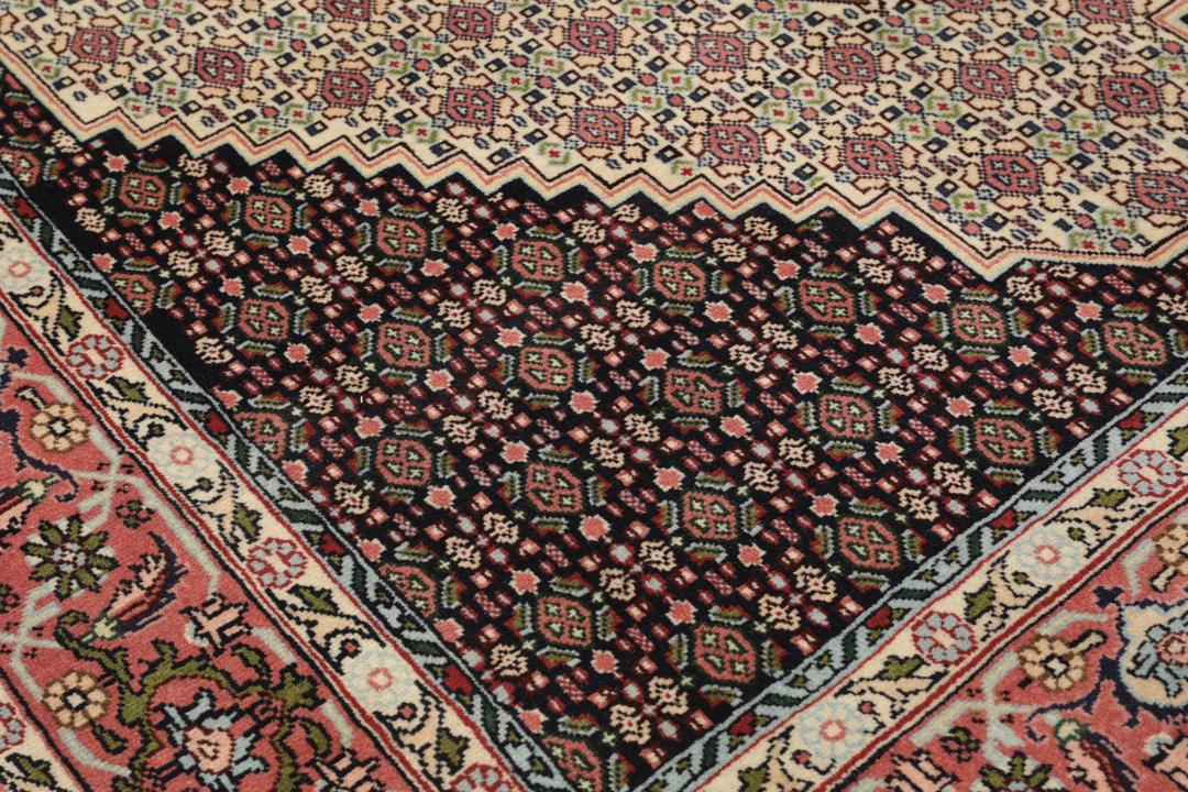 A hand-knotted Senneh rug from the Middle East featuring a dark-red and cream geometric medallion design.