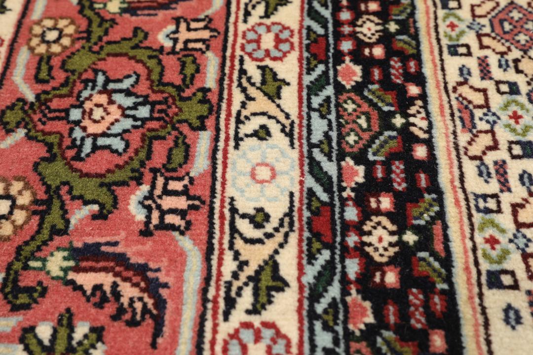 A hand-knotted Senneh rug from the Middle East featuring a dark-red and cream geometric medallion design.