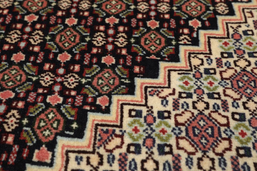 A hand-knotted Senneh rug from the Middle East featuring a dark-red and cream geometric medallion design.