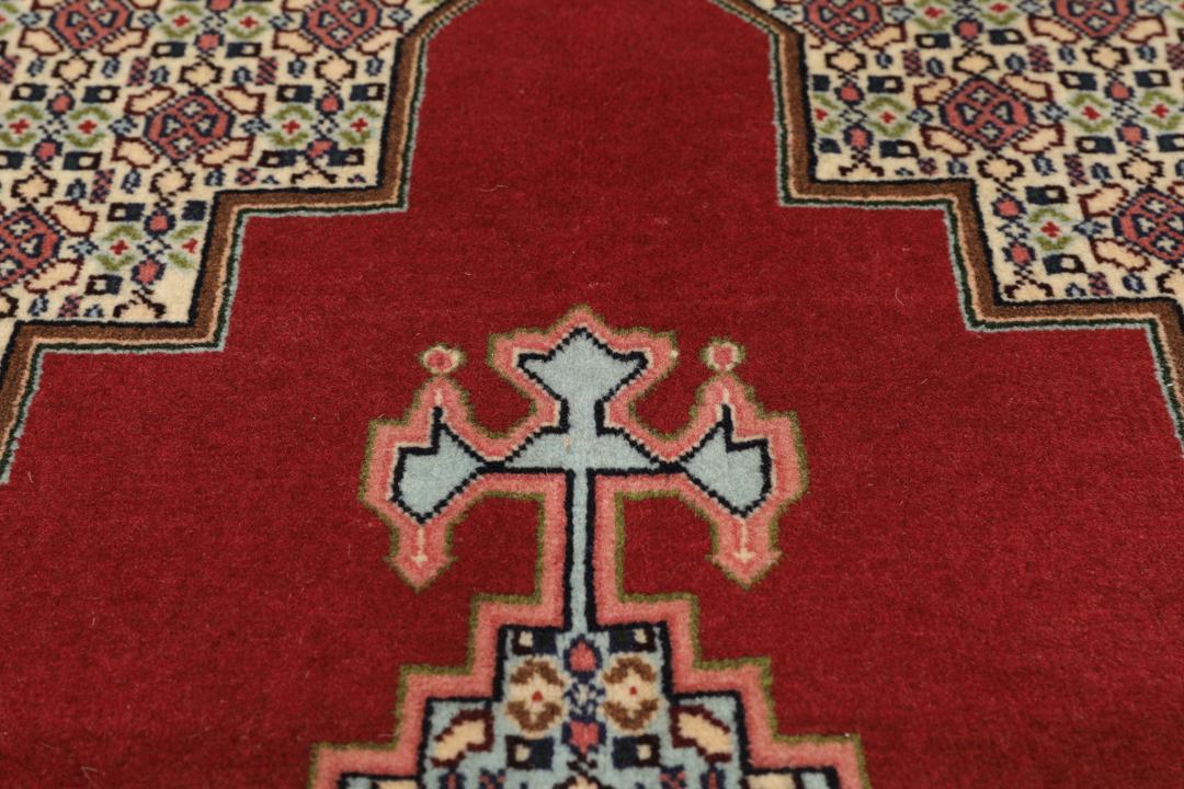 A hand-knotted Senneh rug from the Middle East featuring a dark-red and cream geometric medallion design.