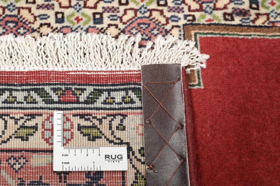 A hand-knotted Senneh rug from the Middle East featuring a dark-red and cream geometric medallion design.