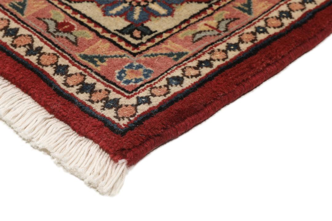 Een met de hand geknoopt Ardebil-tapijt uit het Midden-Oosten met een rood veld en ingewikkelde geometrische patronen.