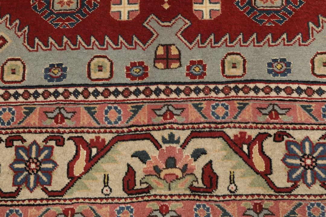 Een met de hand geknoopt Ardebil-tapijt uit het Midden-Oosten met een rood veld en ingewikkelde geometrische patronen.