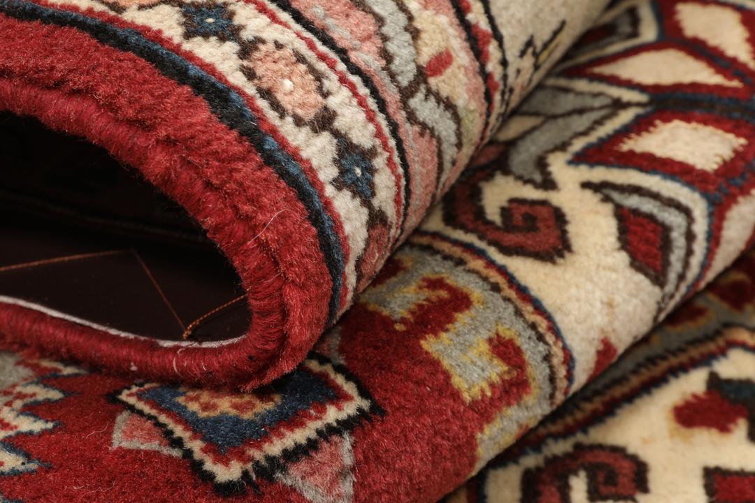 Een met de hand geknoopt Ardebil-tapijt uit het Midden-Oosten met een rood veld en ingewikkelde geometrische patronen.