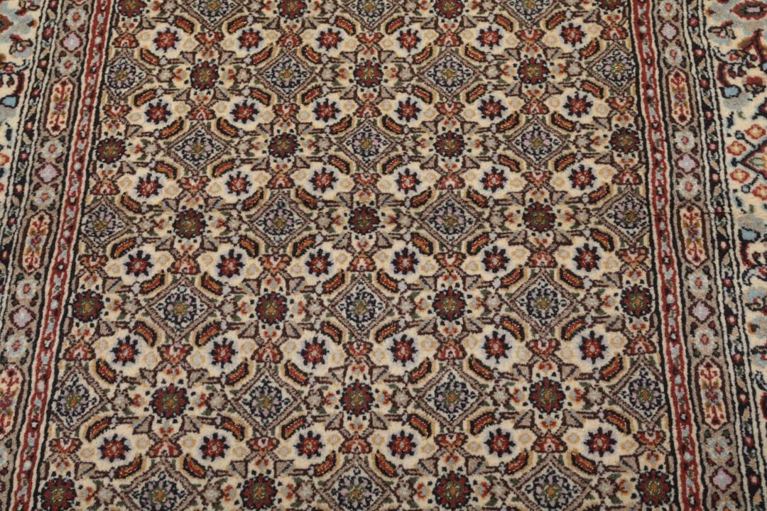 Een handgeknoopt Moud-tapijt uit het Midden-Oosten in beige, rode en blauwe tinten.