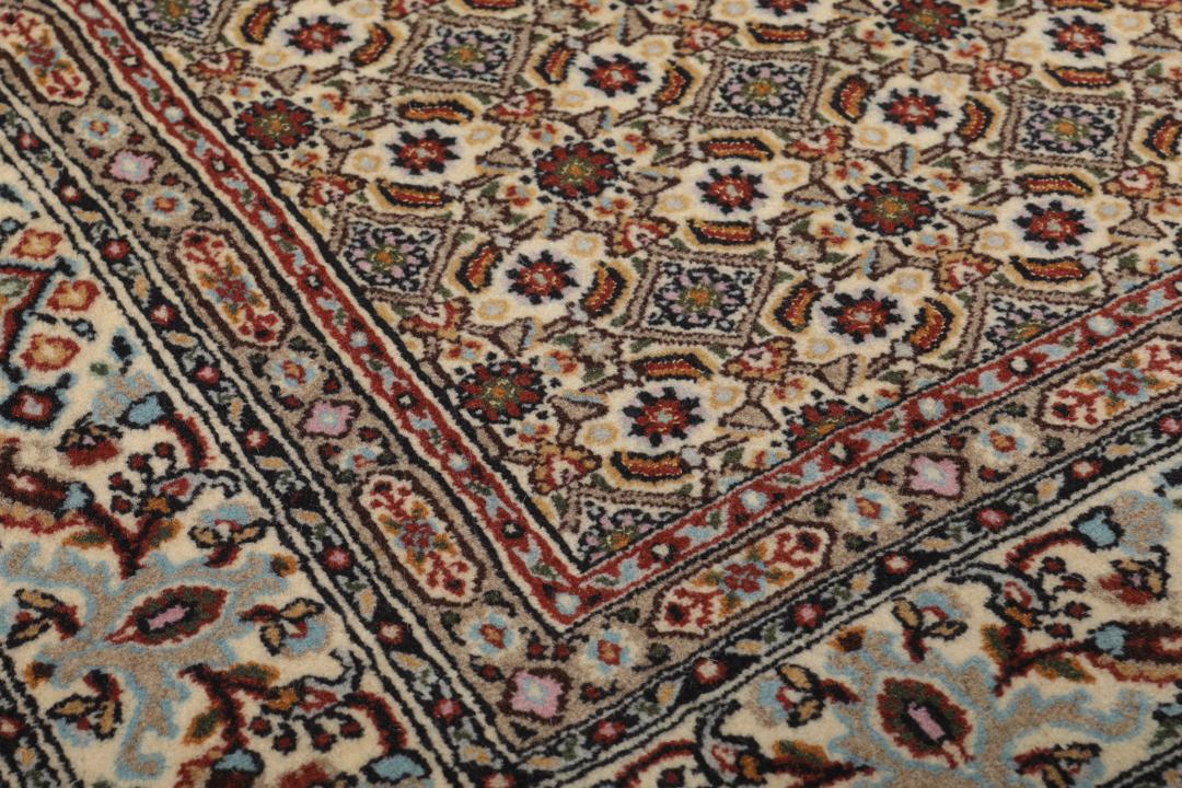 Een handgeknoopt Moud-tapijt uit het Midden-Oosten in beige, rode en blauwe tinten.