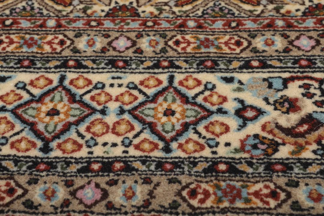 Een handgeknoopt Moud-tapijt uit het Midden-Oosten in beige, rode en blauwe tinten.