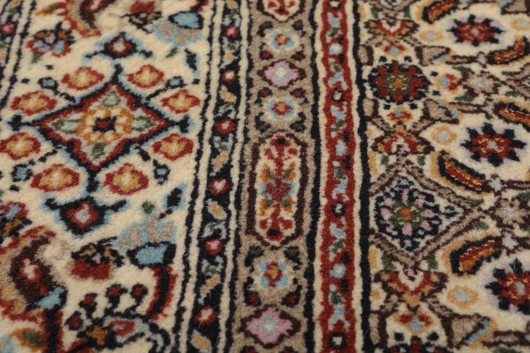 Een handgeknoopt Moud-tapijt uit het Midden-Oosten in beige, rode en blauwe tinten.