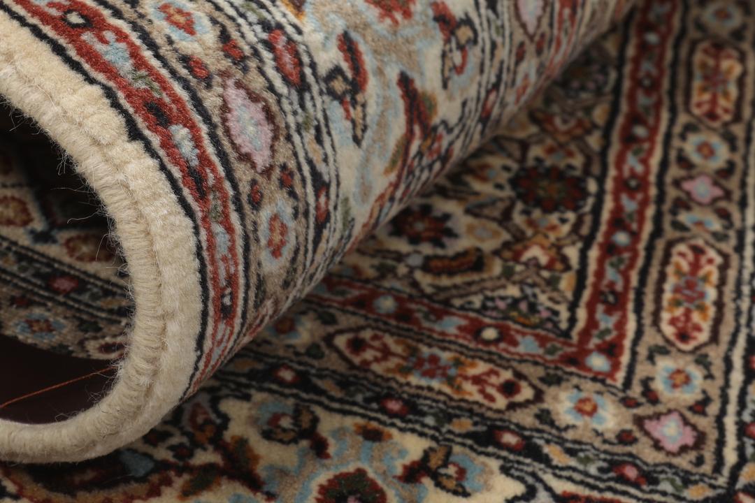 Een handgeknoopt Moud-tapijt uit het Midden-Oosten in beige, rode en blauwe tinten.