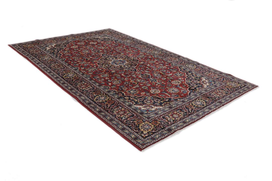Een handgeknoopt Keshan-tapijt uit het Midden-Oosten met een dieprood en marineblauw bloemenmedaillon.