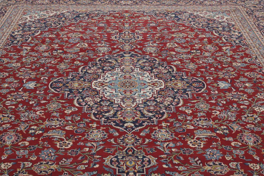 Una alfombra Keshan anudada a mano del Medio Oriente con un campo rojo y bordes azul marino.