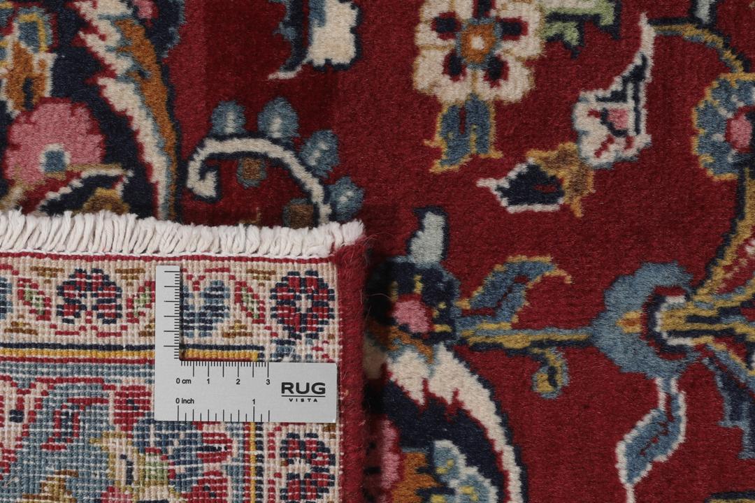 Una alfombra Keshan anudada a mano del Medio Oriente con un campo rojo y bordes azul marino.