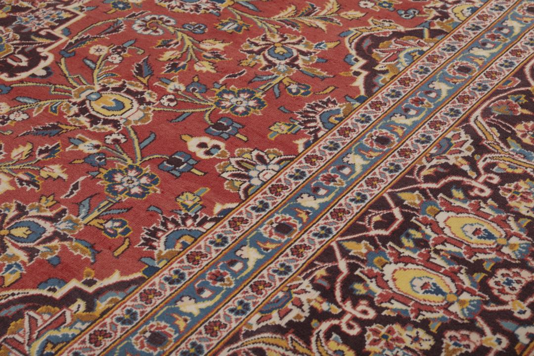 A large hand-knotted Keshan rug from the Middle East with a red floral pattern.