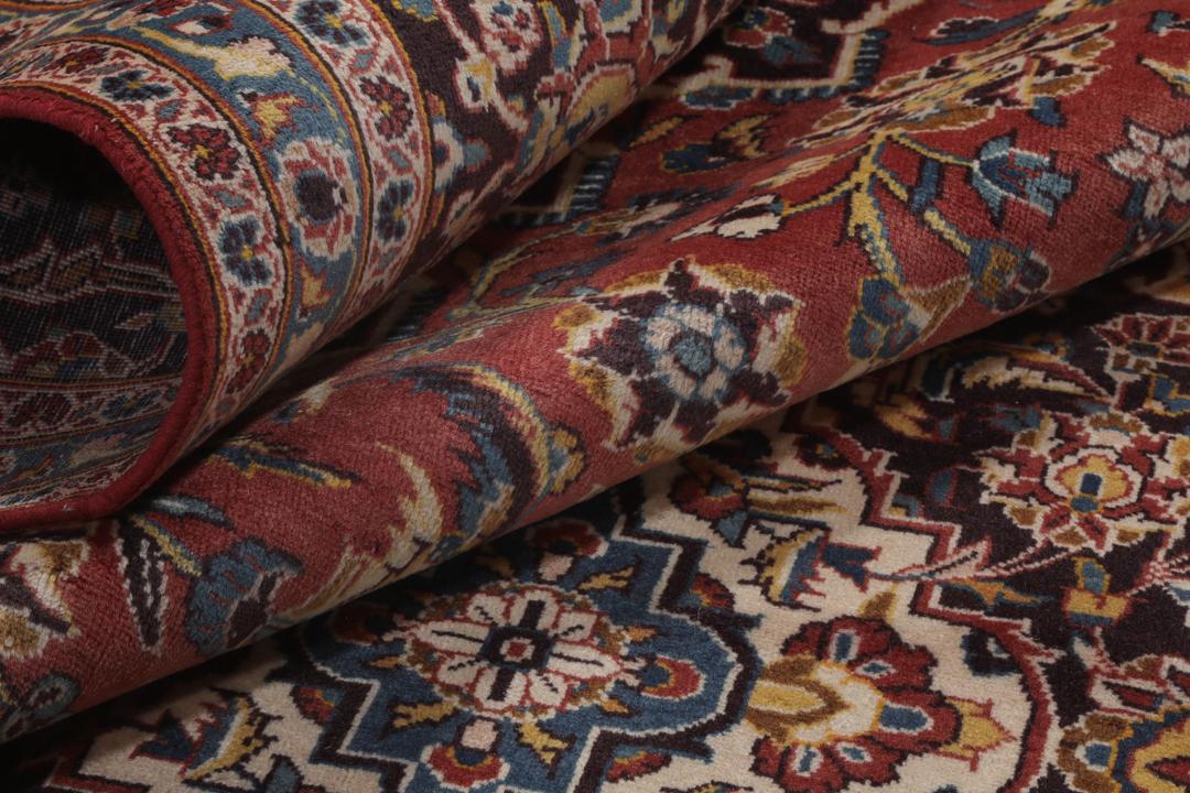 A large hand-knotted Keshan rug from the Middle East with a red floral pattern.