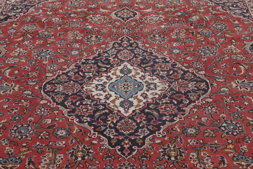 A hand-knotted Keshan rug from the Middle East with a red and dark-blue medallion pattern.