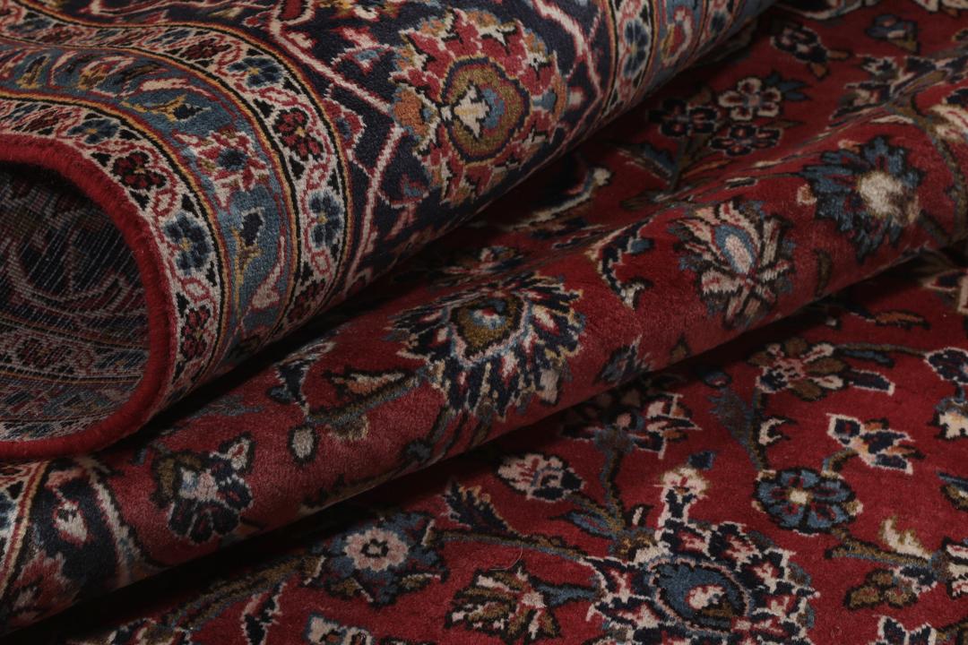 A hand-knotted Keshan rug from the Middle East with a red and dark-blue medallion pattern.
