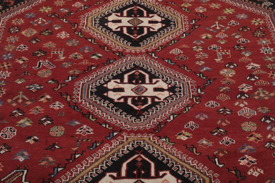 Een handgeknoopt Shiraz-tapijt uit het Midden-Oosten met een donkerrood en zwart kleurenpalet met tribale motieven