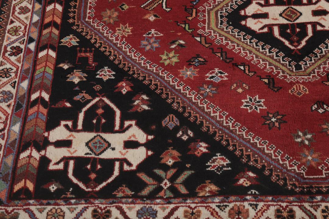 Een handgeknoopt Shiraz-tapijt uit het Midden-Oosten met een donkerrood en zwart kleurenpalet met tribale motieven