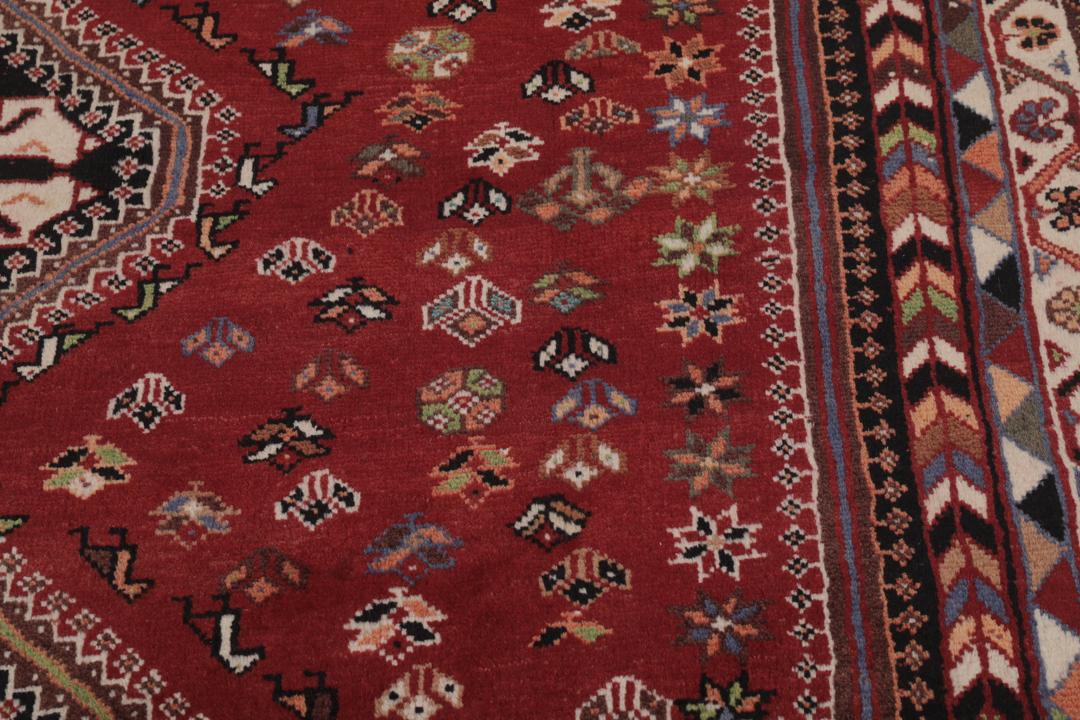 Een handgeknoopt Shiraz-tapijt uit het Midden-Oosten met een donkerrood en zwart kleurenpalet met tribale motieven