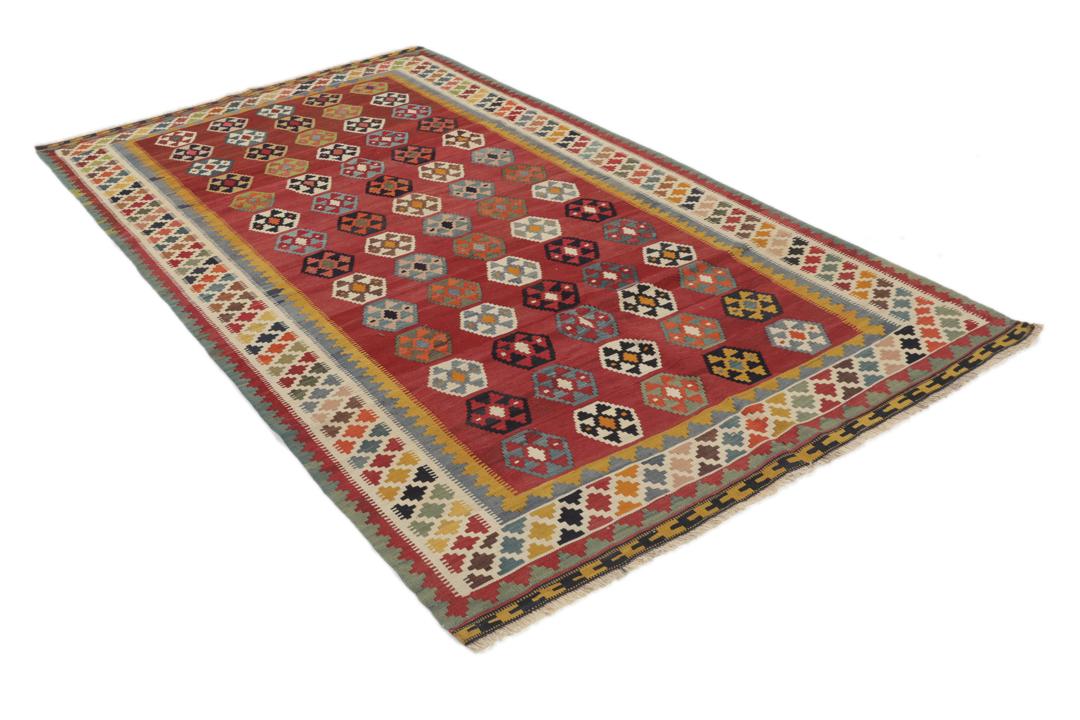 Een vintage handgeweven kelimkleed uit het Midden-Oosten met een rood veld en kleurrijke geometrische patronen.