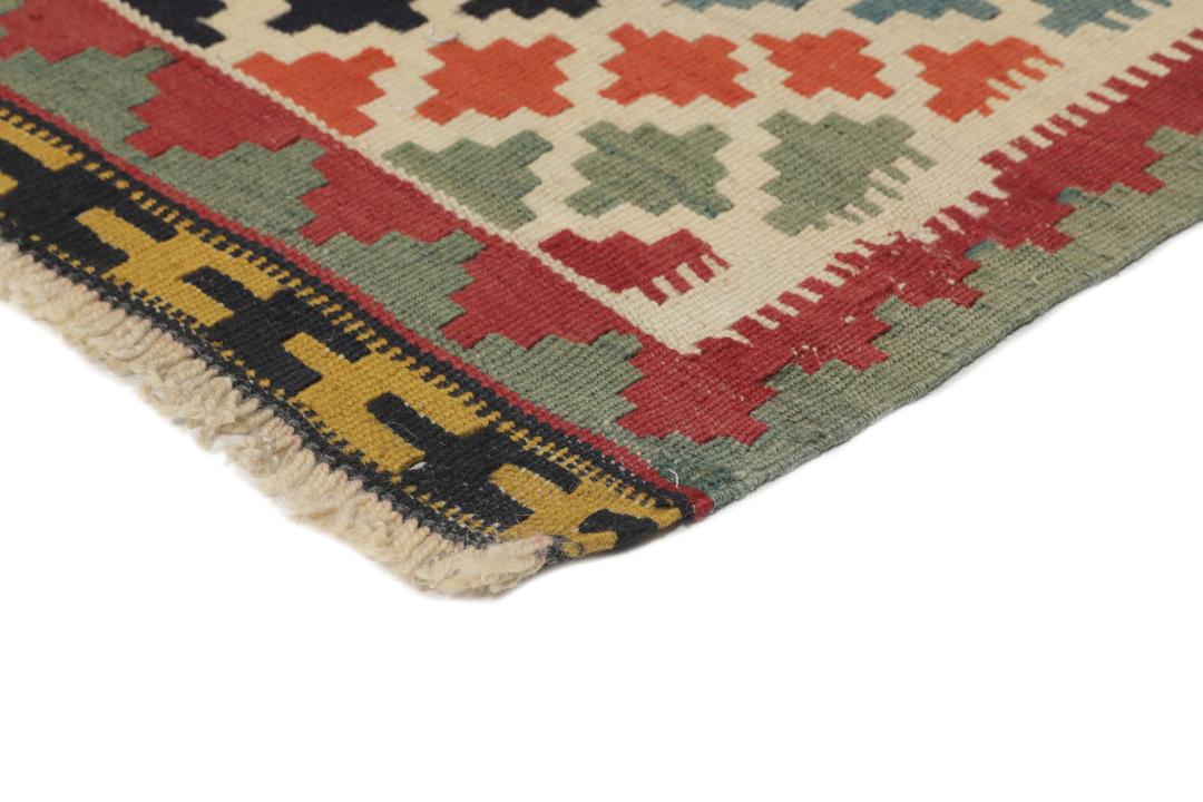 Een vintage handgeweven kelimkleed uit het Midden-Oosten met een rood veld en kleurrijke geometrische patronen.