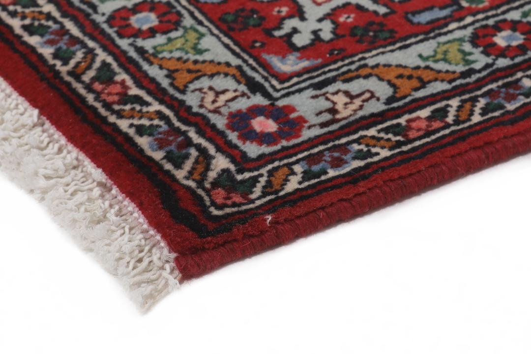 Een handgeknoopt rood Senneh-tapijt met een centraal medaillonpatroon uit het Midden-Oosten.