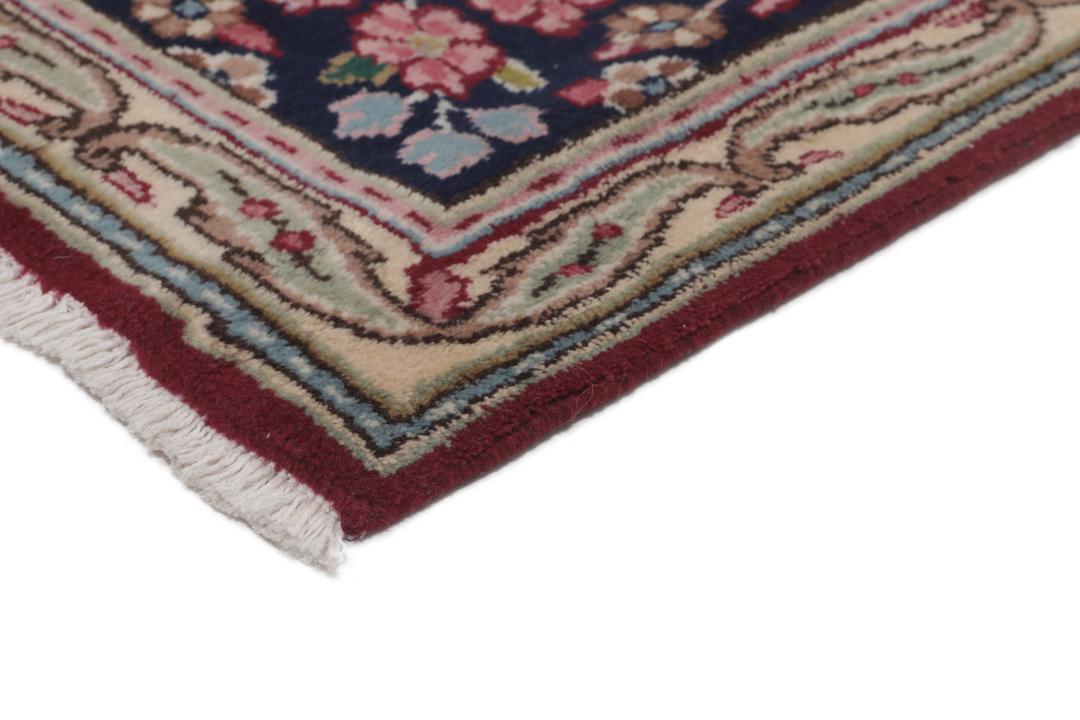A hand-knotted Kerman rug with a red field and intricate floral medallion patterns.