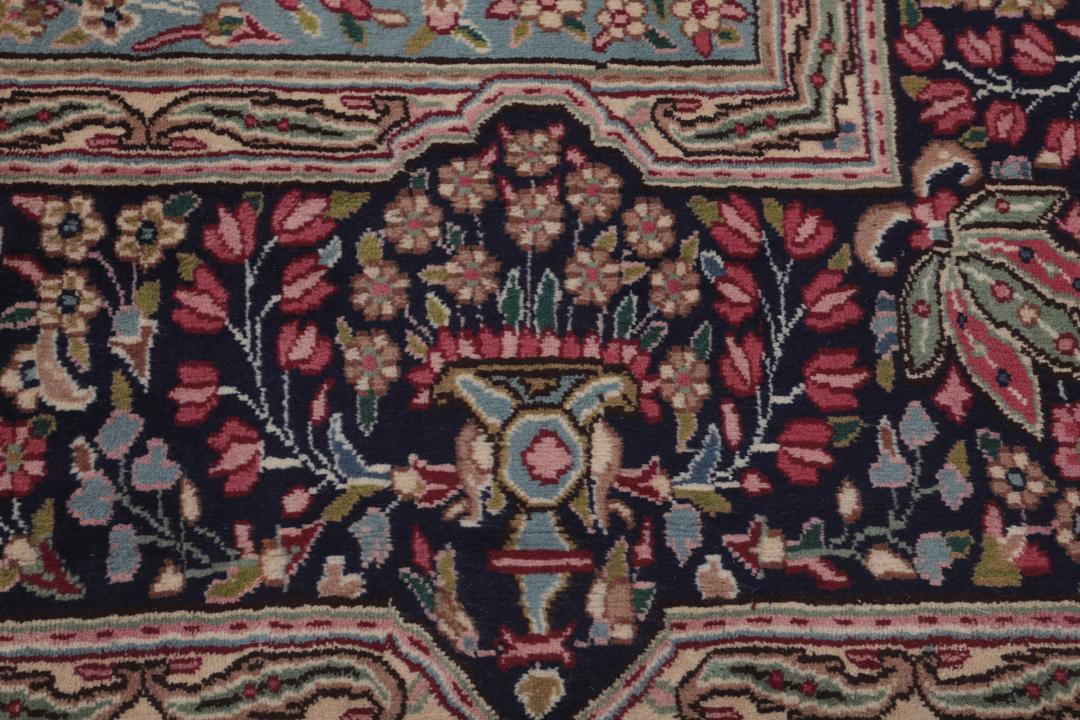 A hand-knotted Kerman rug with a red field and intricate floral medallion patterns.