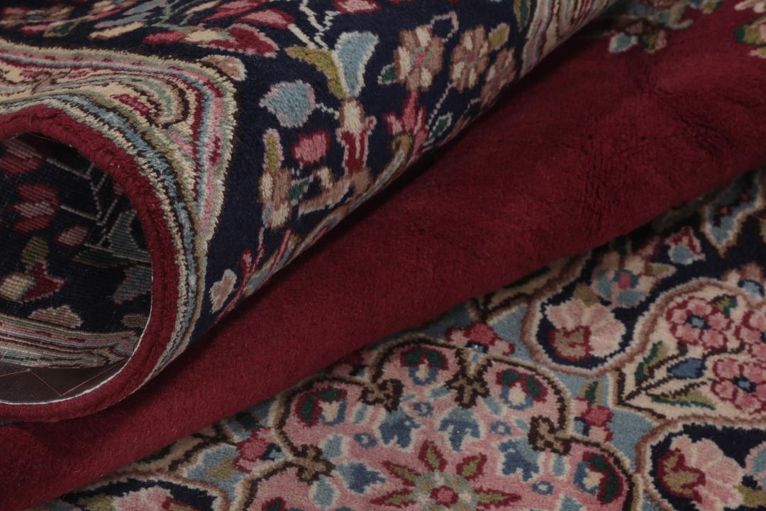 A hand-knotted Kerman rug with a red field and intricate floral medallion patterns.