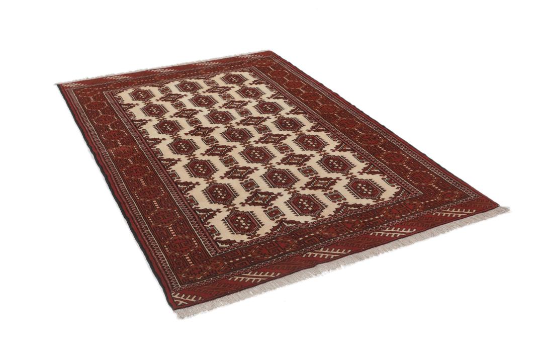 Een handgeknoopt Turkaman-tapijt met geometrische medaillons in rode en beige tinten.