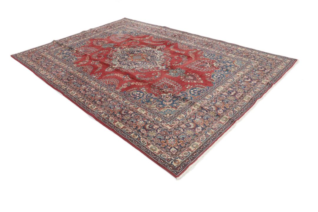 A hand-knotted red Mashad rug featuring a traditional floral medallion design