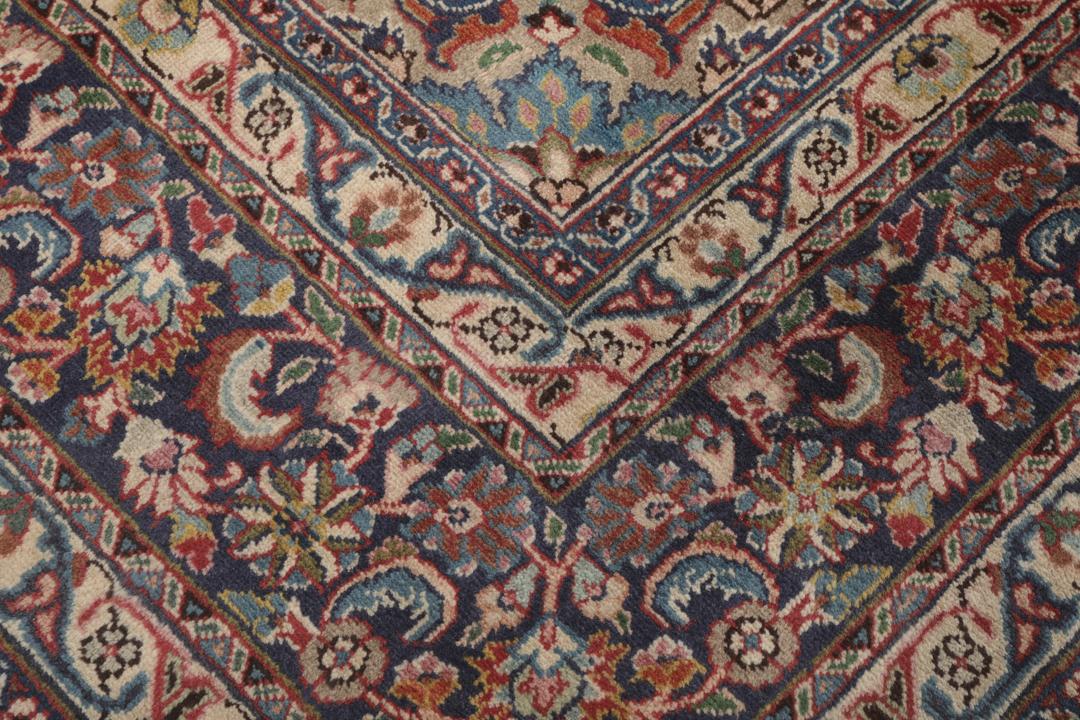 A hand-knotted red Mashad rug featuring a traditional floral medallion design