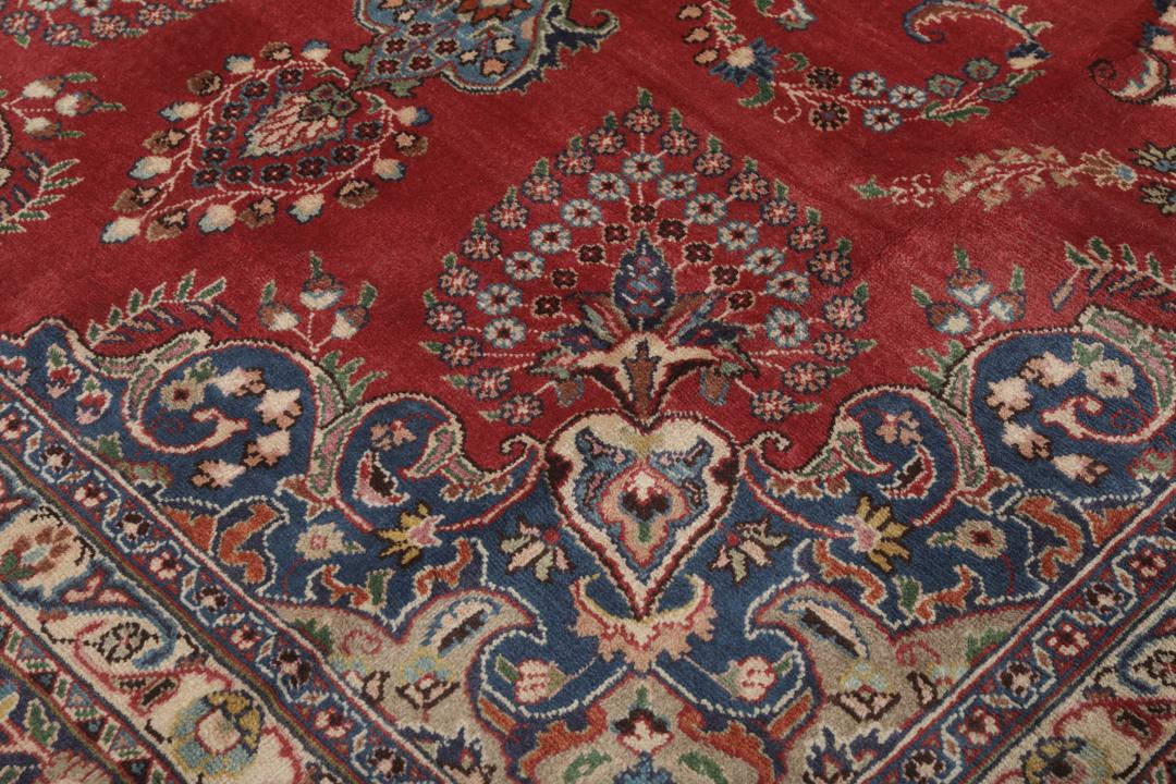 A hand-knotted red Mashad rug featuring a traditional floral medallion design