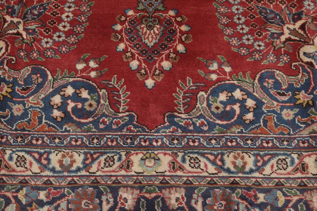 A hand-knotted red Mashad rug featuring a traditional floral medallion design