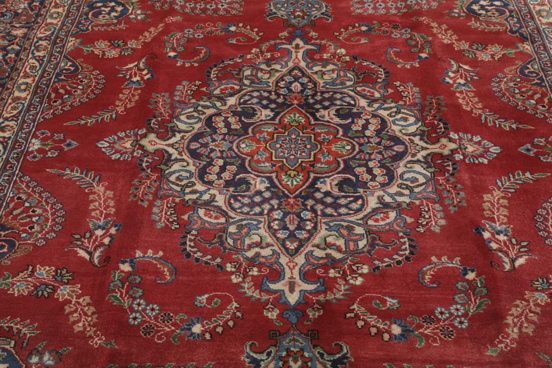 A hand-knotted red Mashad rug featuring a traditional floral medallion design