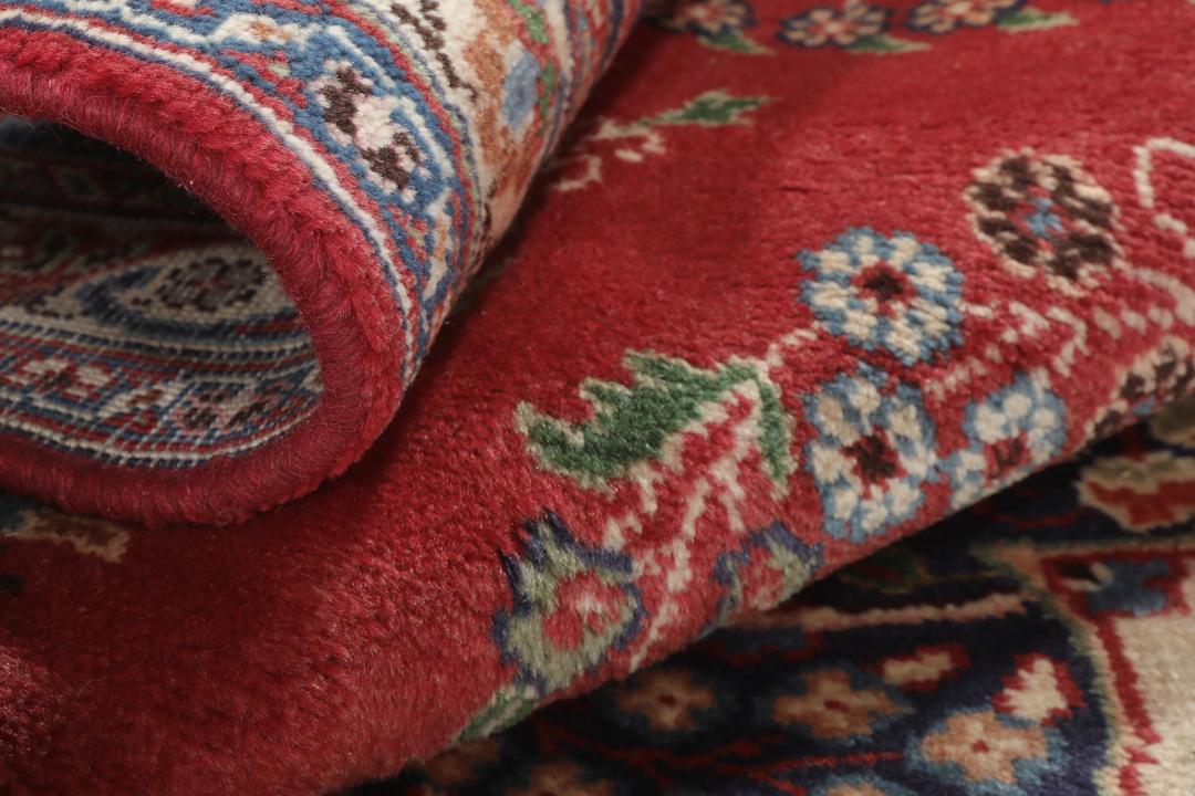 A hand-knotted red Mashad rug featuring a traditional floral medallion design