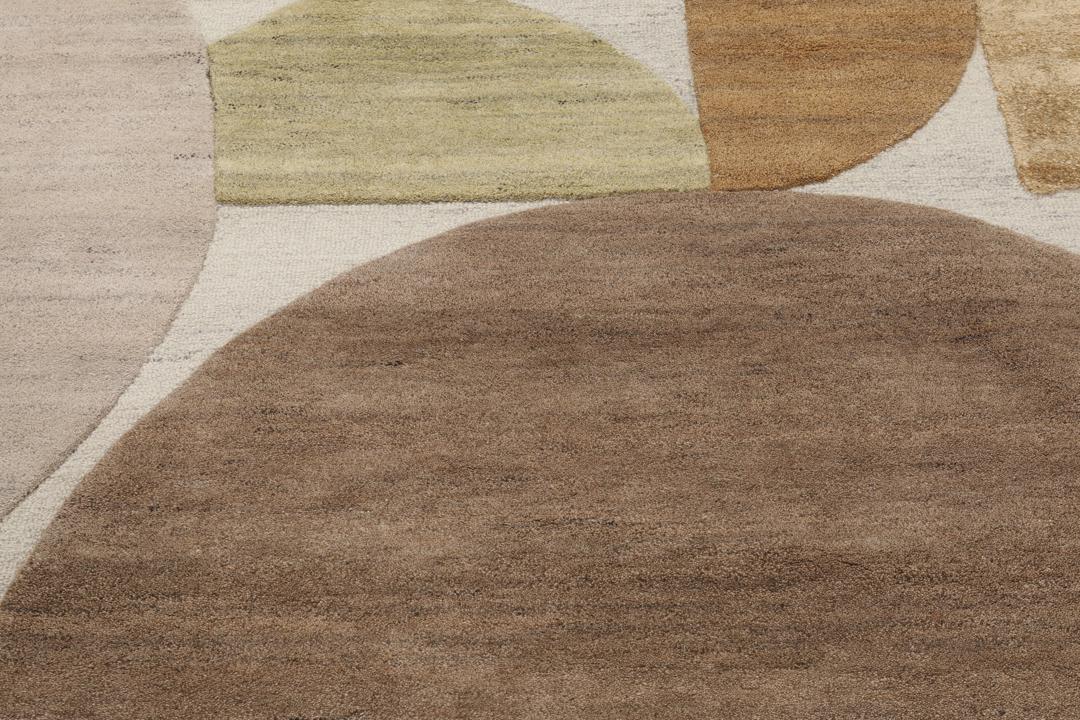 Een modern wollen tapijt in bruin en beige met een geometrisch cirkelpatroon.