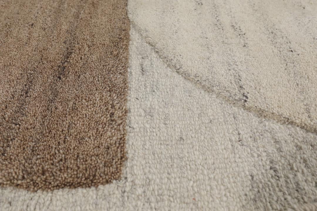 Een modern wollen tapijt in bruin en beige met een geometrisch cirkelpatroon.