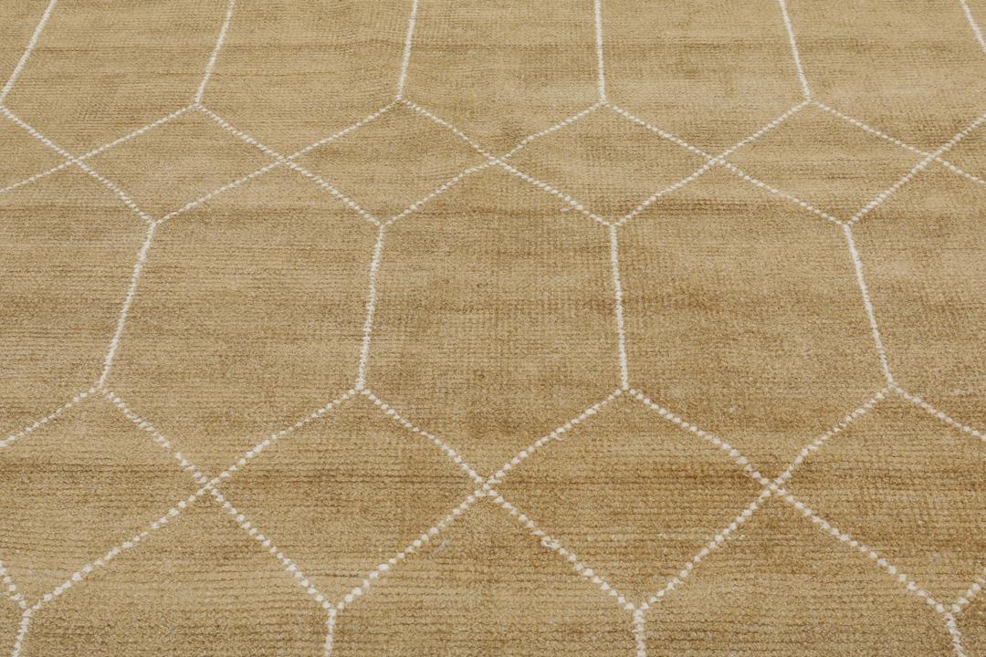 Et gyldent tæppe med et hvidt geometrisk gittermønster
