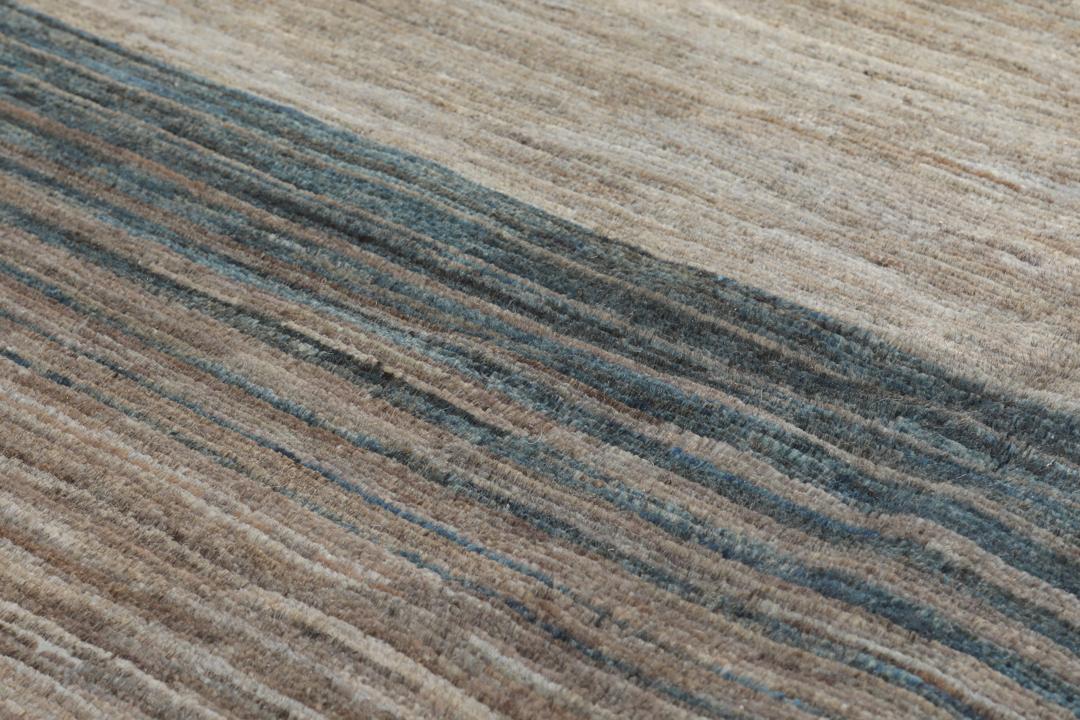 Et håndknyttet Gabbeh-tæppe fra Afghanistan med en horisontal gradient i nuancer af grå og blå.