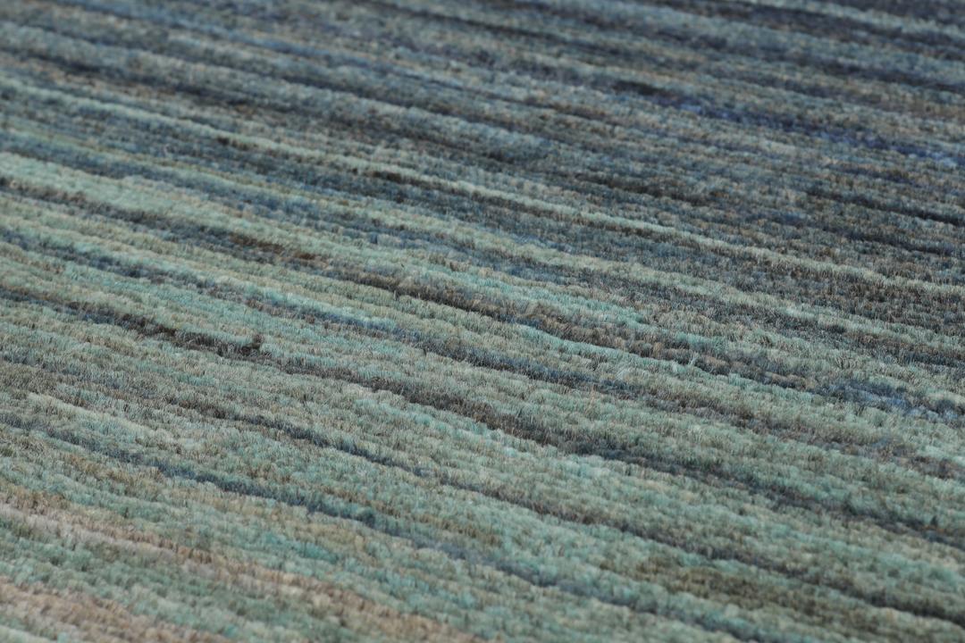 Et håndknyttet Gabbeh-tæppe fra Afghanistan med en horisontal gradient i nuancer af grå og blå.