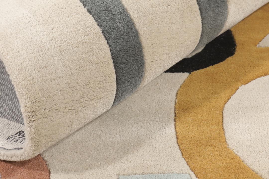 Et beige tæppe med et legende, flerfarvet talmønster.